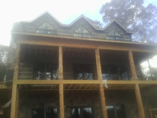 Dormers and porch framing on a large log home under construction — Roof Coating work by our crew in Burkeville