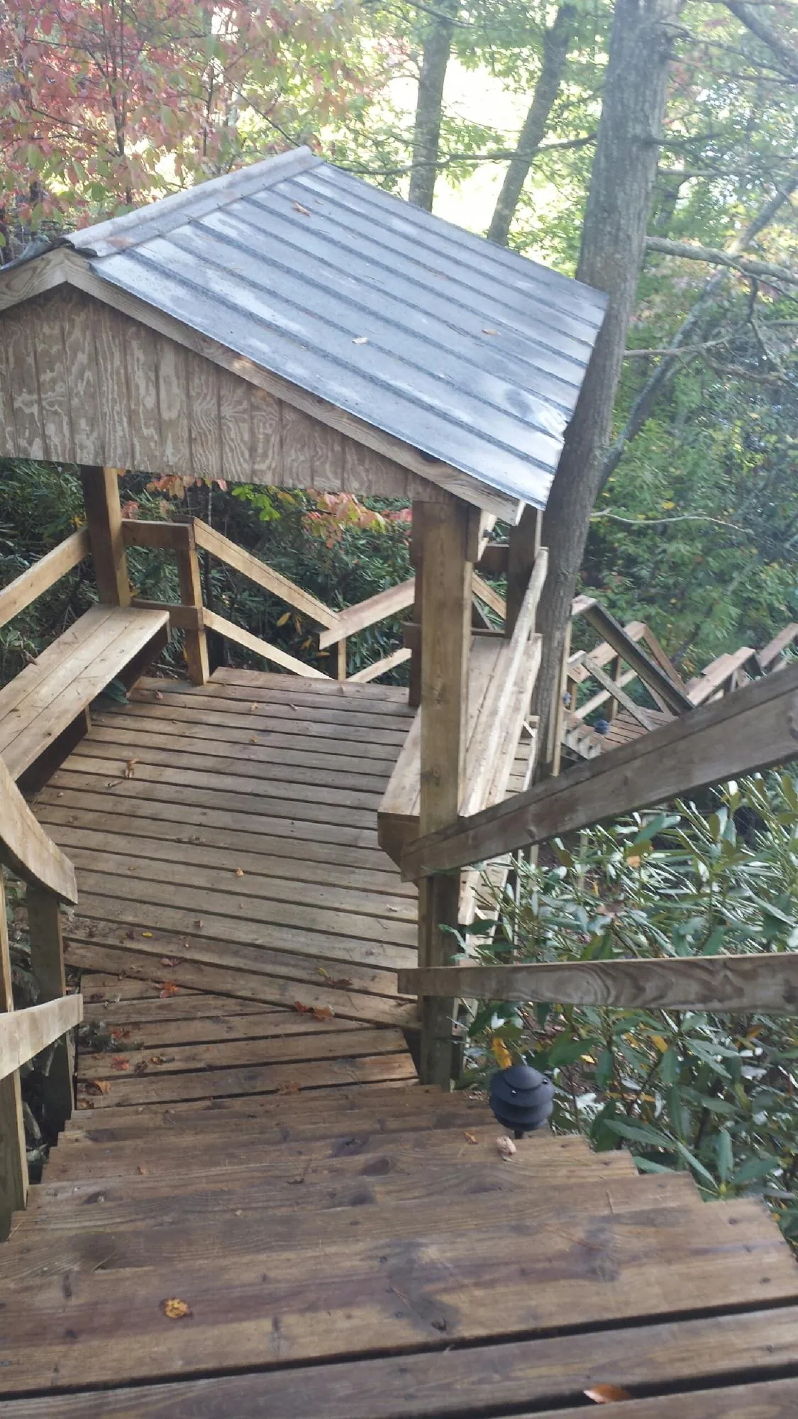 Metal roofed shelter over wooden steps on a wooded walkway — Skylight Repair & Installation work by our crew in Burkeville