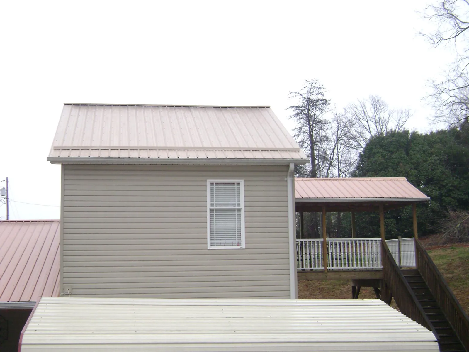 Tan metal roofs on a two story addition and attached porch, from a Roof Replacement job in Burkeville